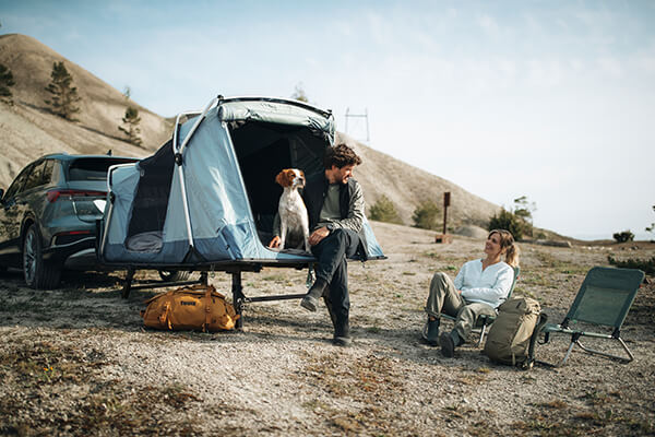 A couple together relax with their dog beside their towball tent