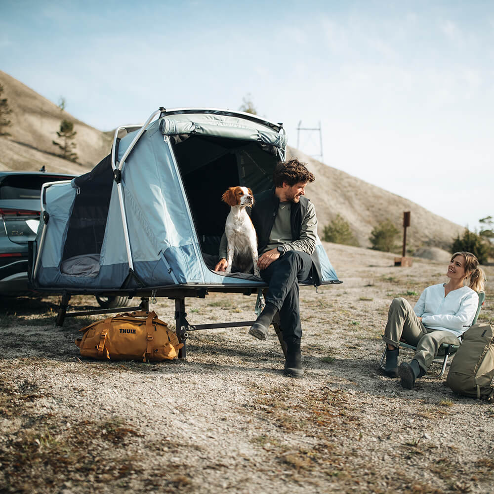 A couple relax with their dog in their Thule Outset towbar tent